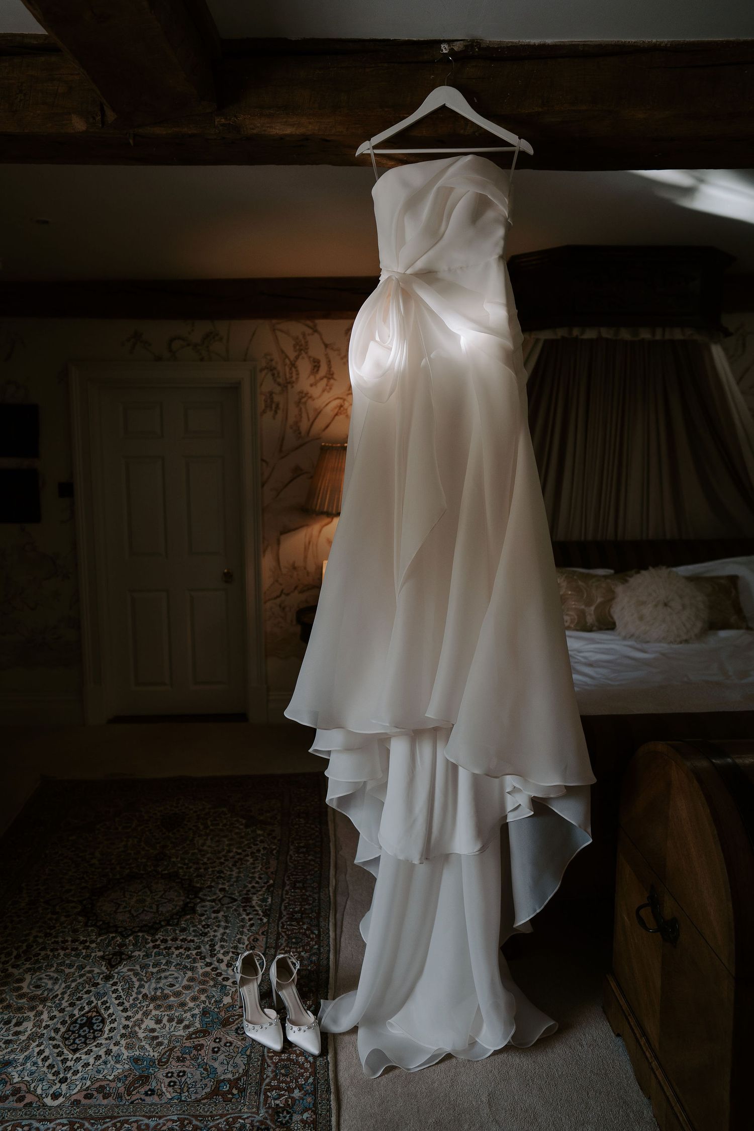 brides wedding dress and shoes hung up before she got dressed at dewsall court in herefordshire