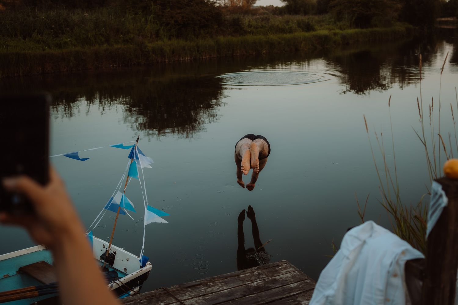 Wedding guests lift a blue cloth over their heads during an outdoor celebration at sunset.