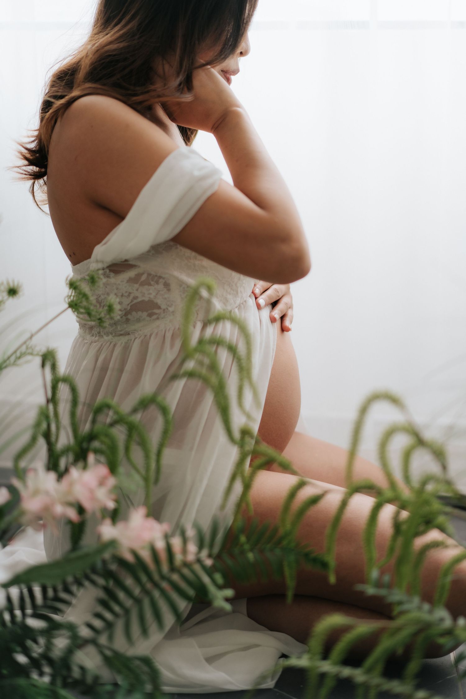 A cake smash photography session featuring white balloons, greenery decorations, and rustic wooden elements.