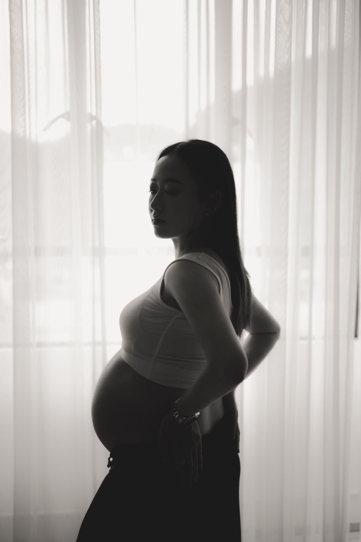 Maternity photo in warm tones featuring a knit sweater and dried floral wreath wall decor in a cozy bedroom setting.