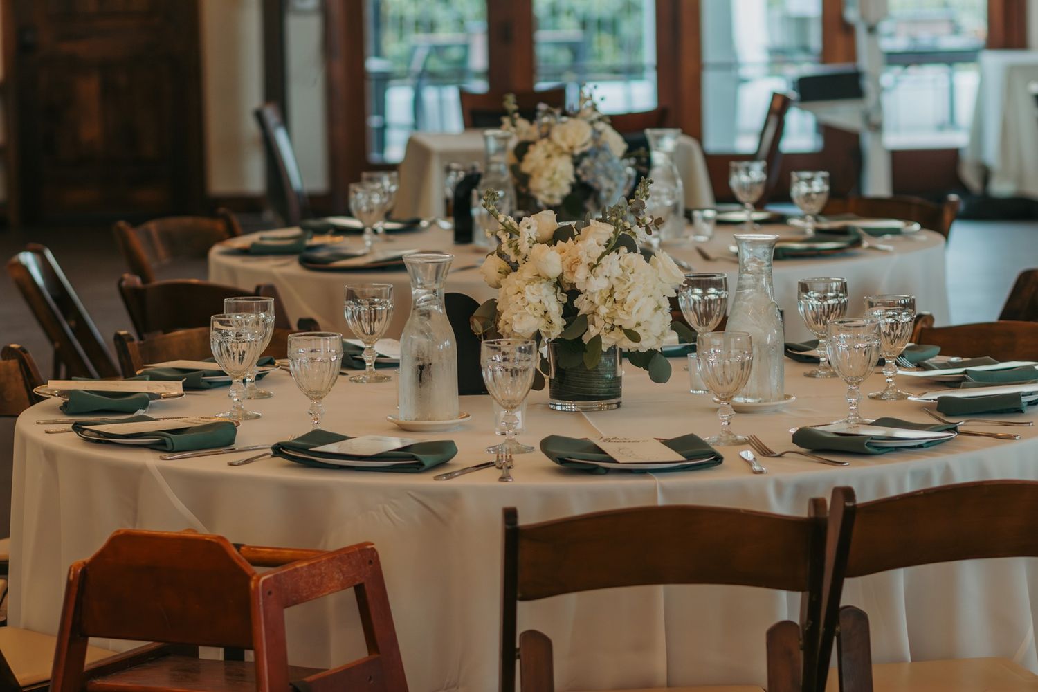 Elegant wedding reception tables set with white linens, floral centerpieces, and formal place settings at San Clemente Shores .