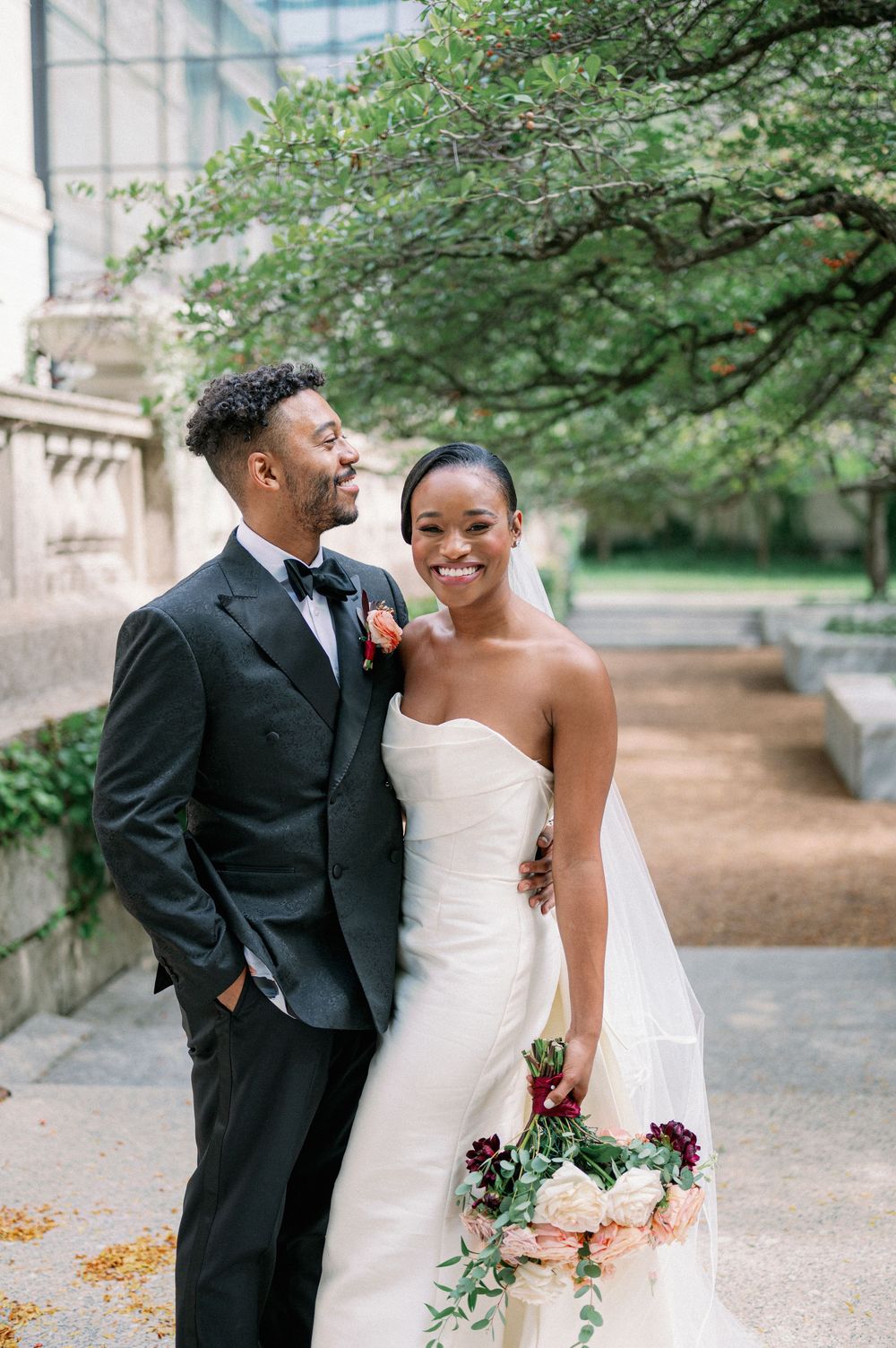 Newlyweds share romantic moment in garden setting with bride holding floral bouquet. - Fairlie Chicago Wedding