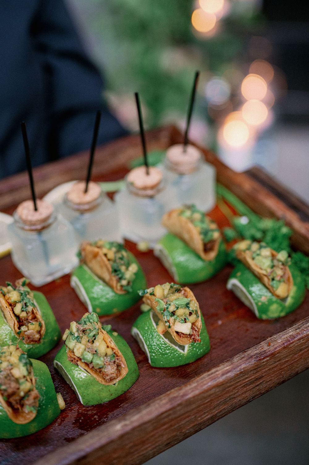 Elegant appetizers of stuffed green lettuce cups and mason jar cocktails arranged on a rustic wooden serving board. - Fairlie Chicago