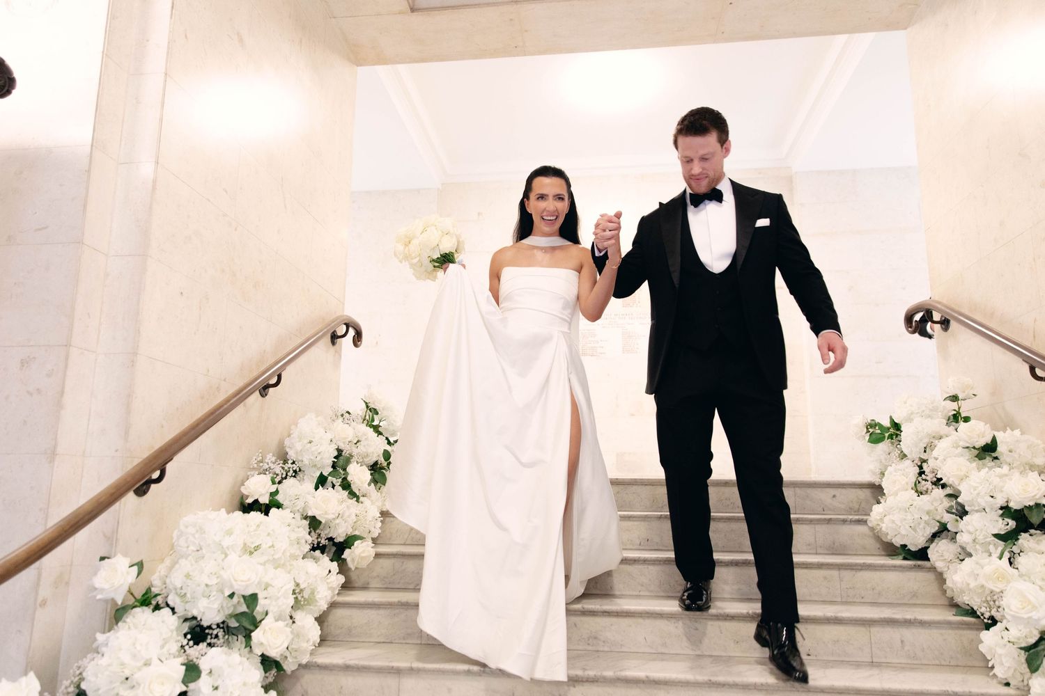 Elegant couple ascending white marble staircase during wedding photoshoot. Old Marylebone town hall