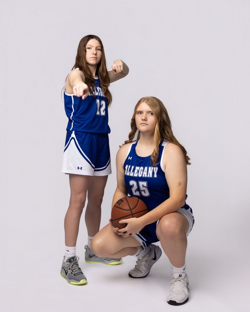 Basketball players in blue and white uniforms pose for team photos in a studio setting.