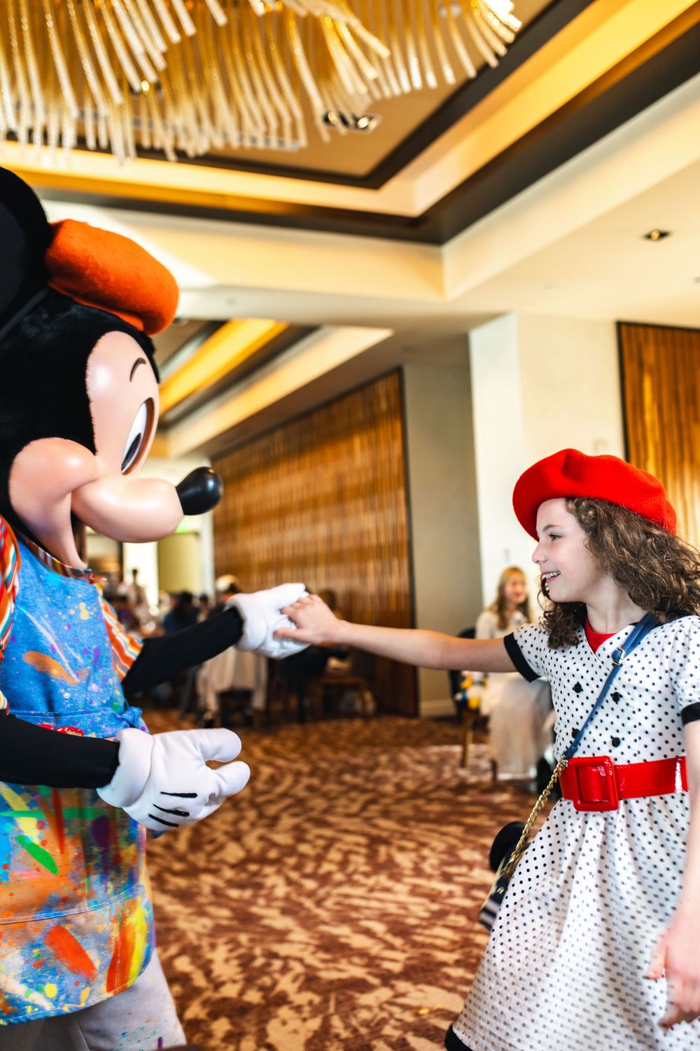 Mickey Mouse character meets with guests in a polka dot dress at a hotel event space.