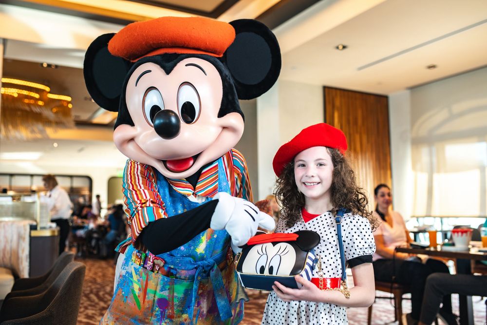 Disney characters Mickey and Minnie Mouse pose with guests at a restaurant during a character dining experience.