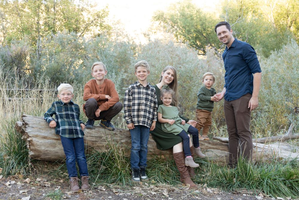 A family poses together on a natural stone ledge surrounded by autumn foliage.
