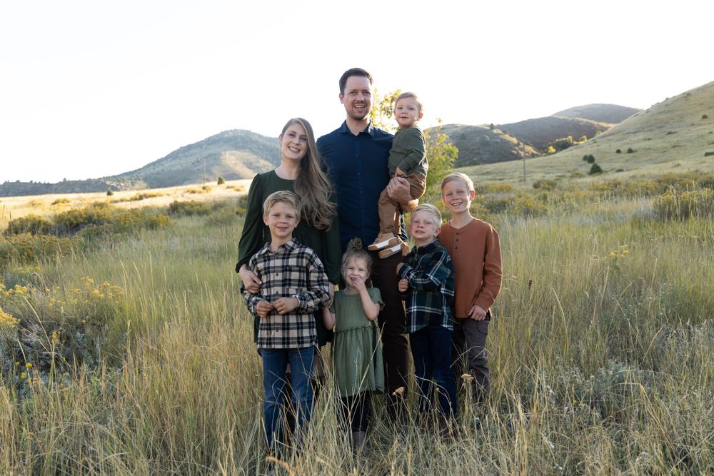 A group portrait in golden grass with mountains in the background at sunset.