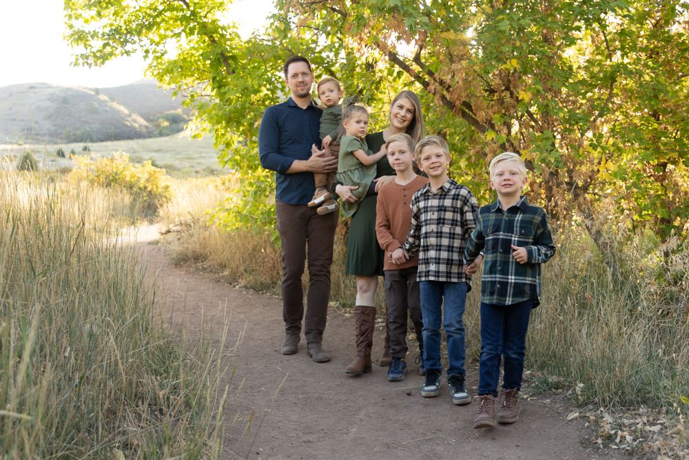 A group stands together on a dirt path surrounded by autumn foliage and tall grass.