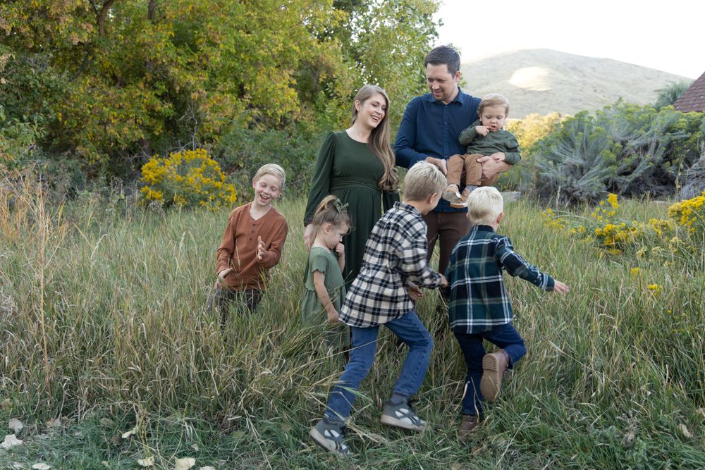 A playful outdoor portrait with people jumping and playing in a field of tall grass.