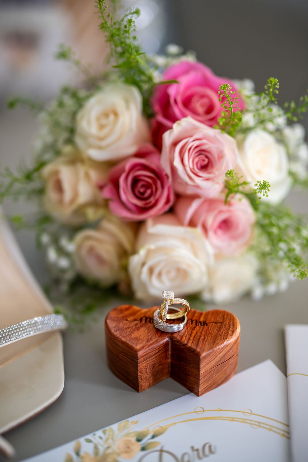Wedding details featuring roses, wooden ring boxes, and elegant invitation cards in a romantic arrangement.