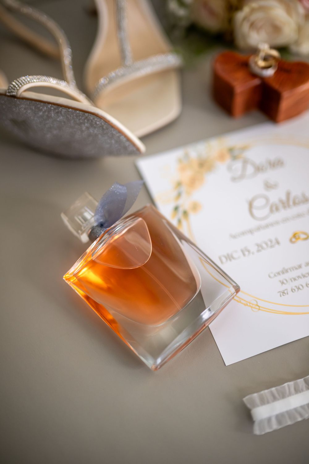 Perfume bottles and floral arrangements displayed alongside wedding stationery with gold accents.