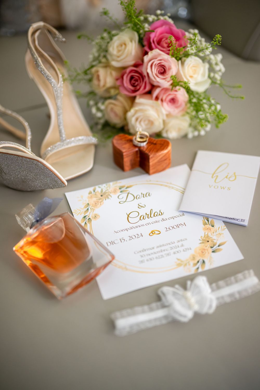Elegant wedding invitation suite with roses, perfume, and decorative elements on a light surface.
