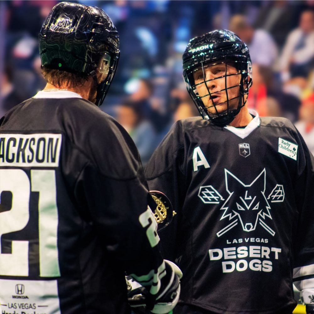 Two Las Vegas Desert Dogs lacrosse players including Jackson number 21 talk during a game.