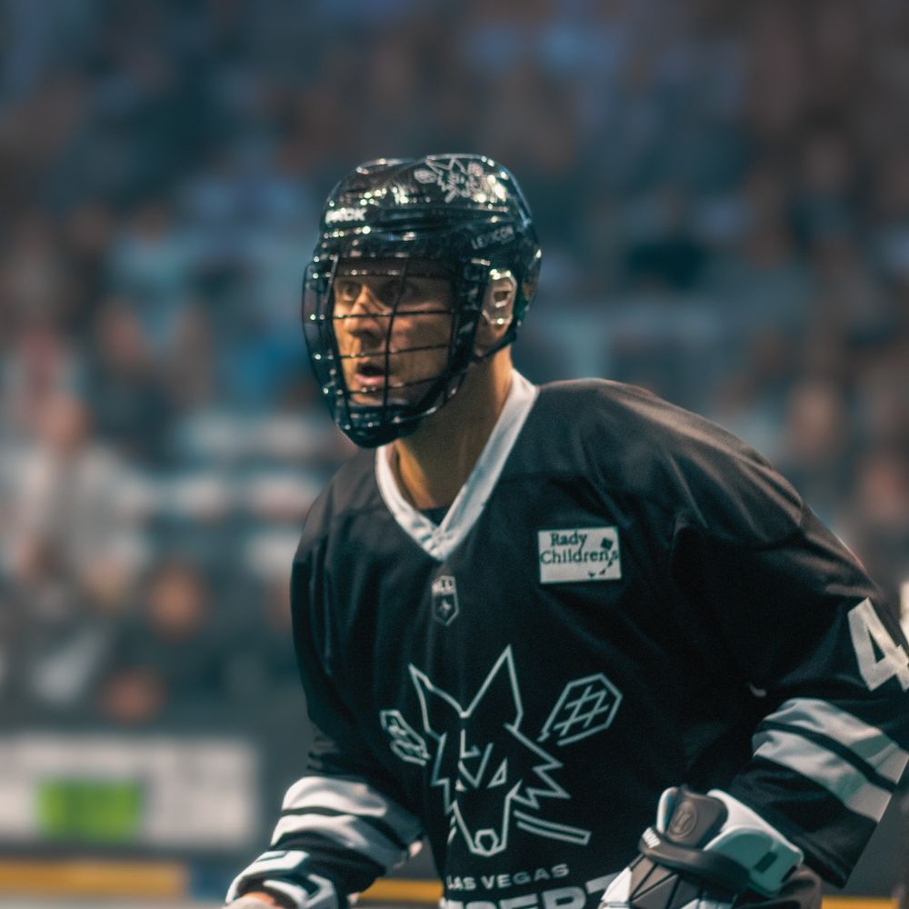A Las Vegas Desert Dogs lacrosse player crouches in a ready stance during an indoor NLL game.