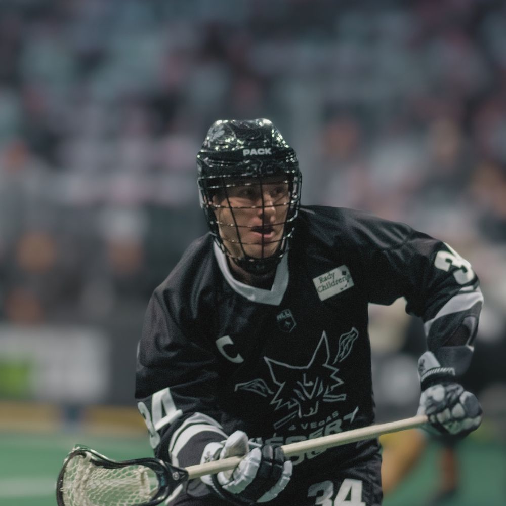 A lacrosse player wearing number 30 runs with a stick during an indoor professional lacrosse game.