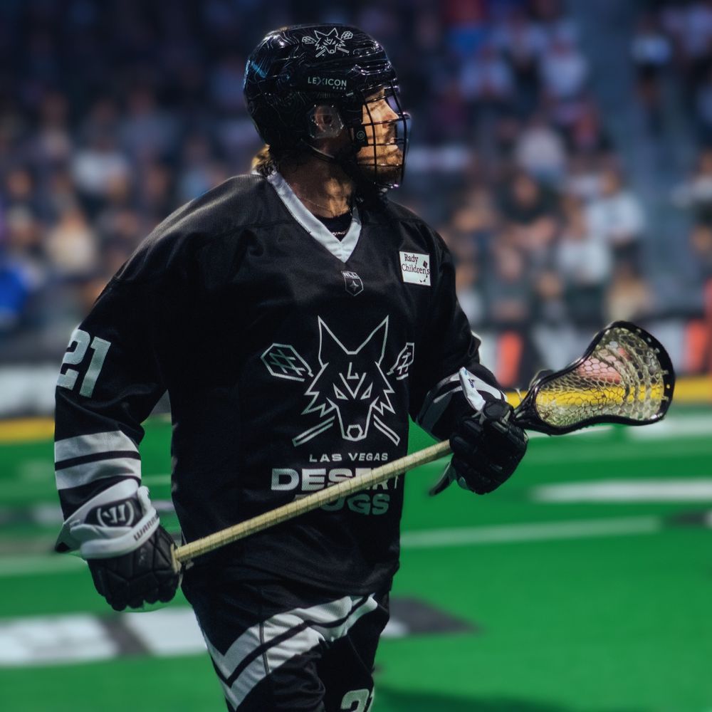 Las Vegas Desert Dogs lacrosse player number 21 holds a stick while running during an NLL game.