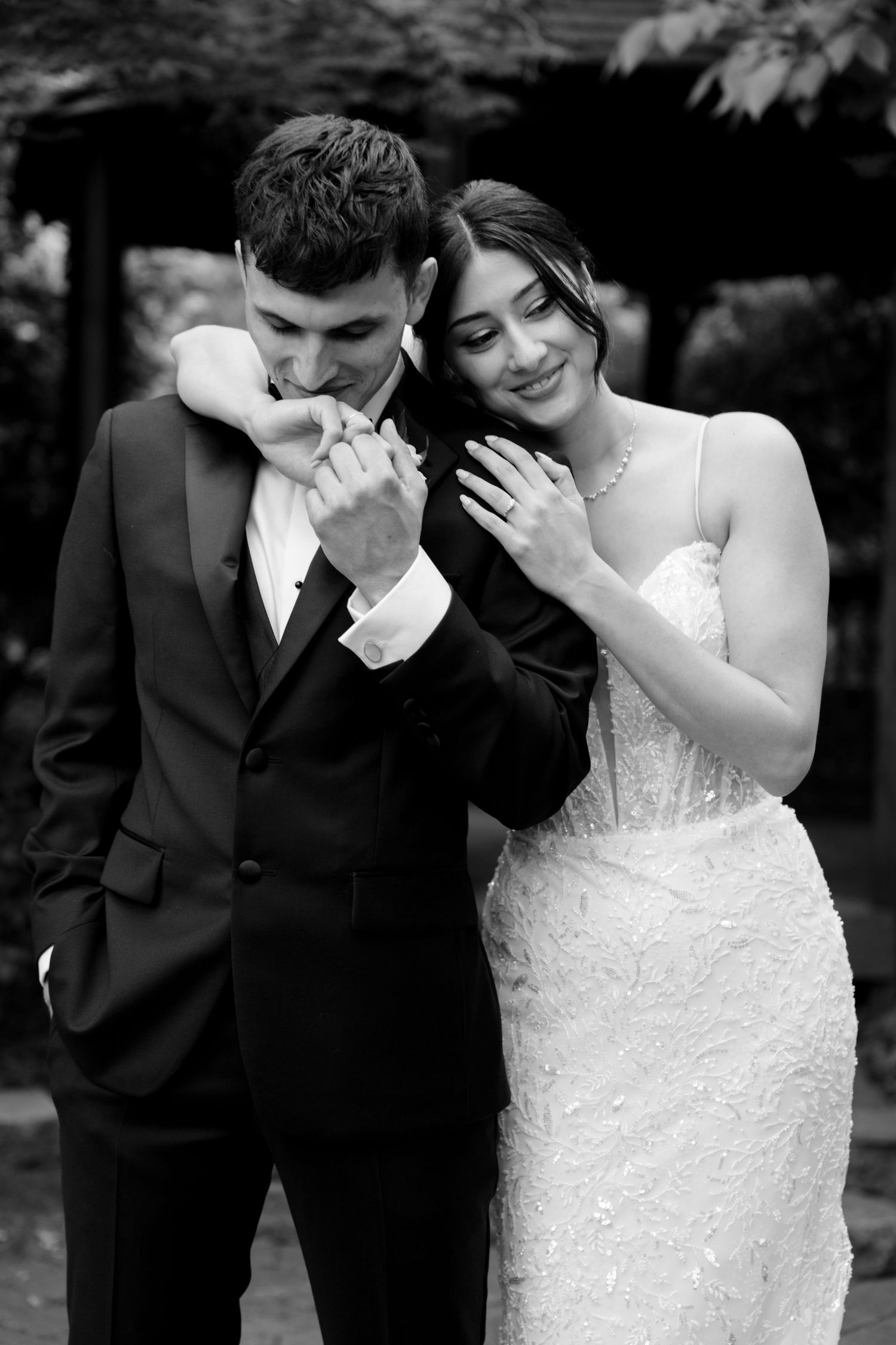 Black and white portrait of newlyweds sharing an intimate moment in formal attire.