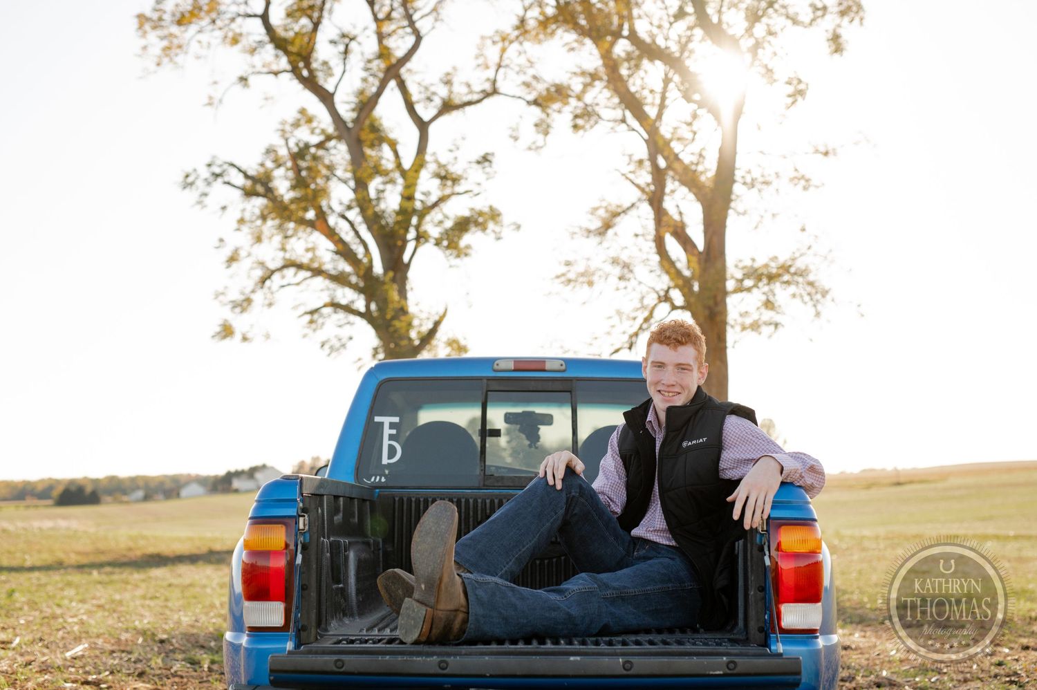 Someone relaxing in the bed of a blue pickup truck at golden hour.