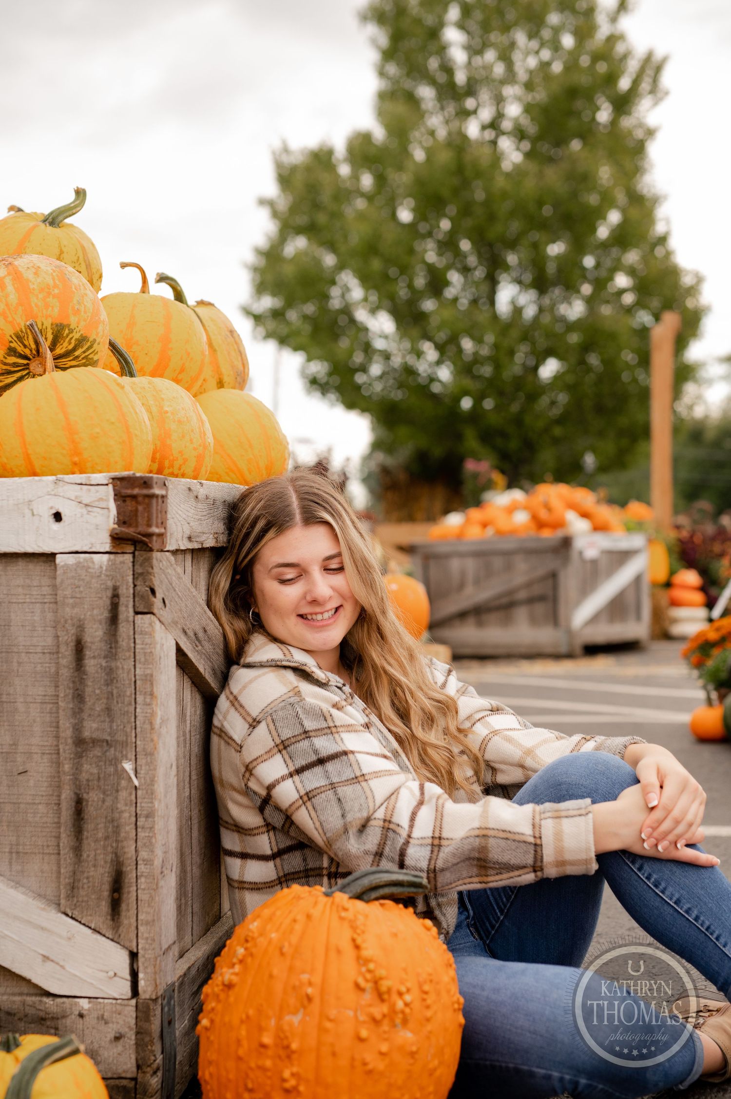 Candid autumn scene of someone relaxing against wooden crates filled with orange pumpkins.