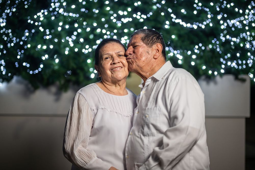 Sweet moment shared between couple wearing white against sparkling blue lights.