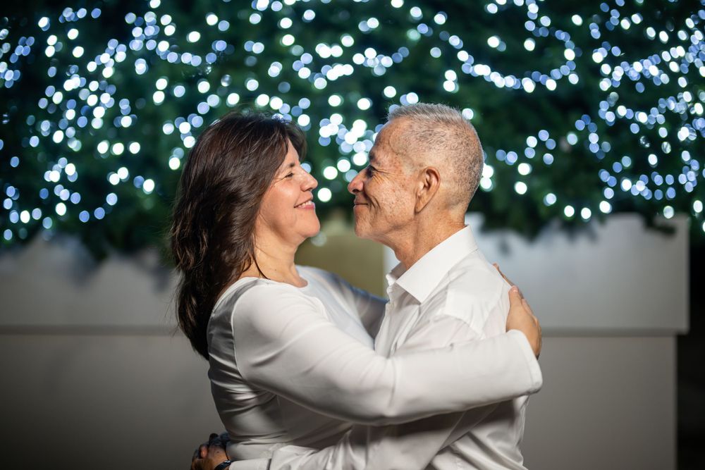 Romantic moment captured in front of twinkling blue lights in an outdoor setting.