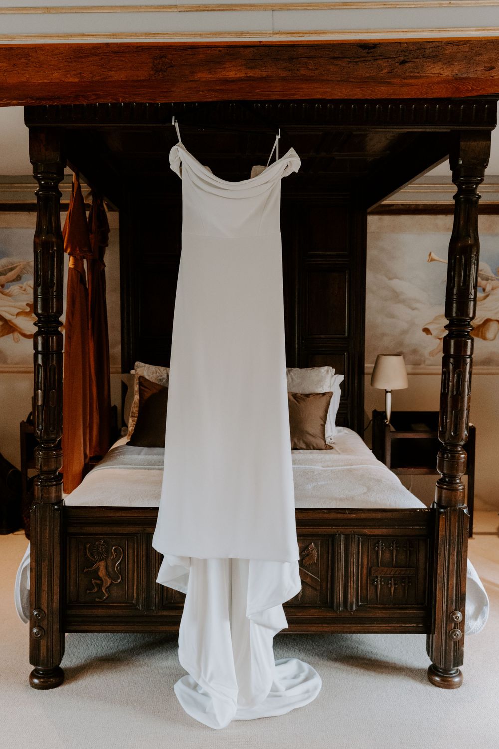 an ivory wedding gown hanging from a four poster bed.