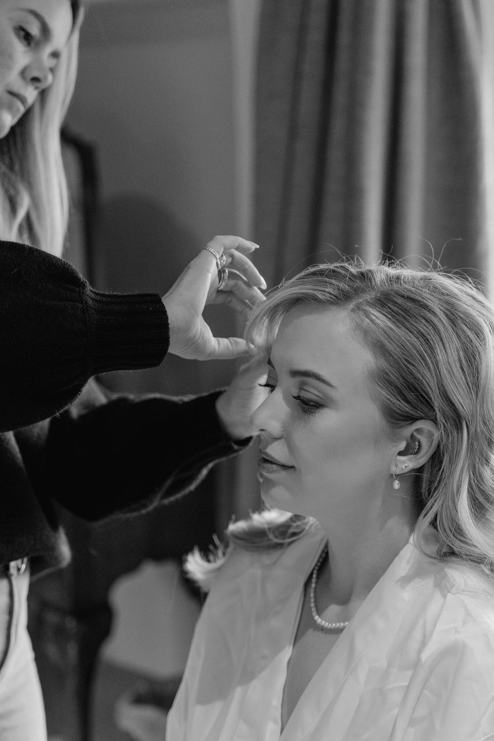 a bride getting her hair finishing touches done. Hairdresser is adding a pearl hair piece.