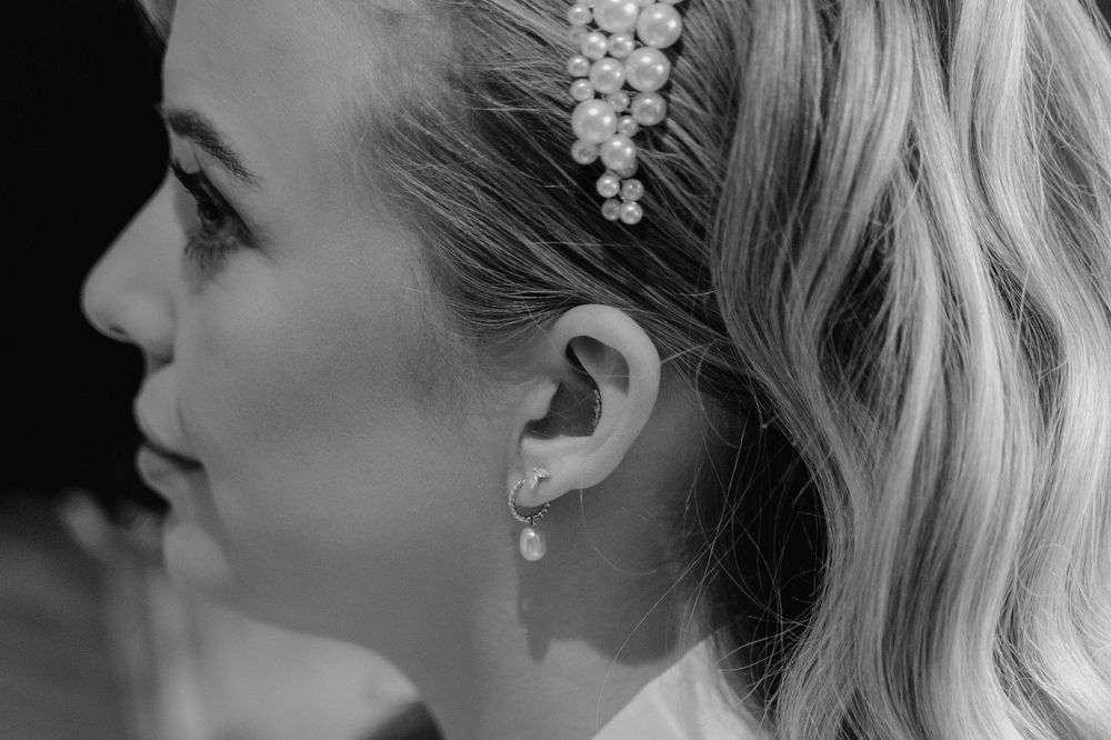 a black and white image of a brides pearl earring in her ear.