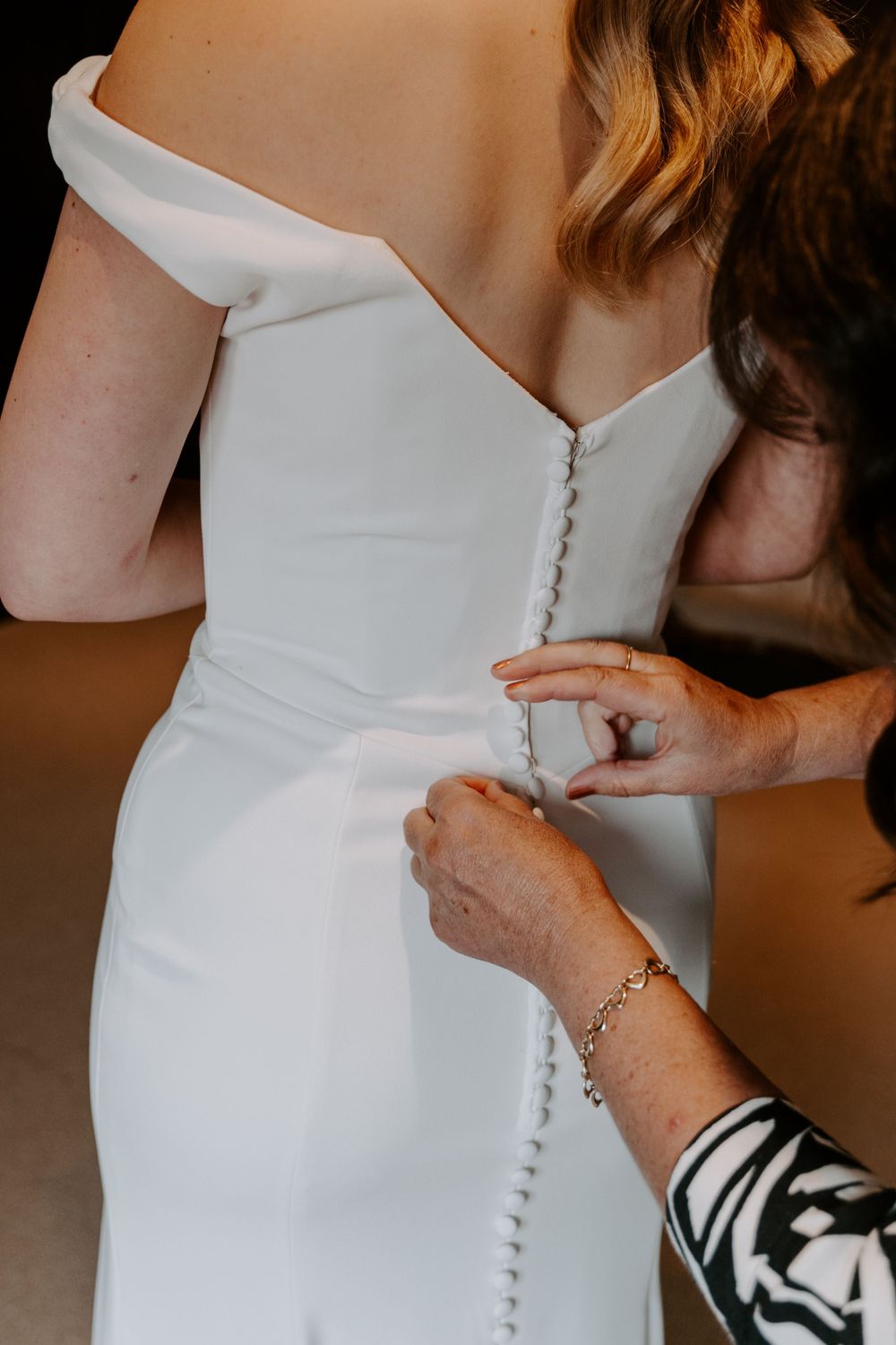 a close up of a brides dress being buttoned up.