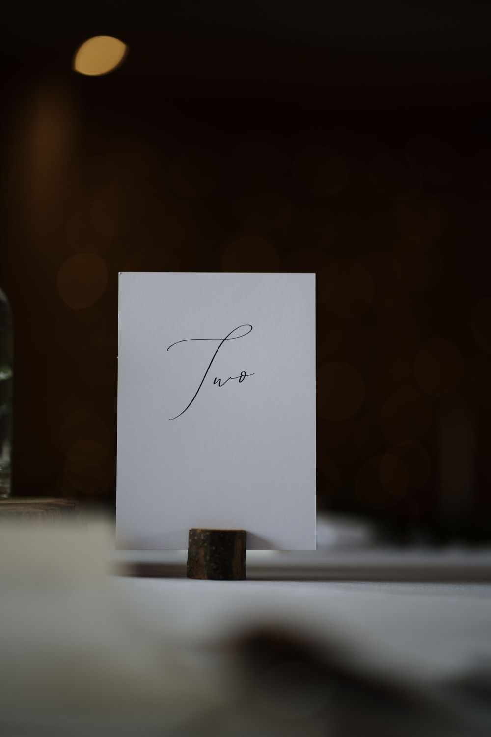 Minimalist table number card displaying 'Two' in elegant calligraphy on white paper.