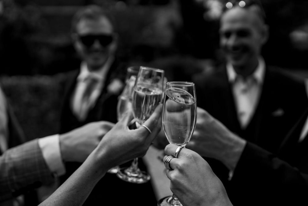 Black and white photo of champagne glasses clinking during a celebratory toast.