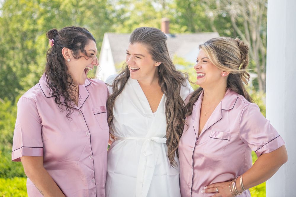 Group wearing coordinated pink and white outfits sharing joyful moment on a sunny porch.