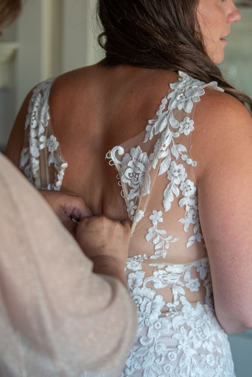 Detailed back view of a wedding gown showing intricate white lace appliques on sheer fabric.