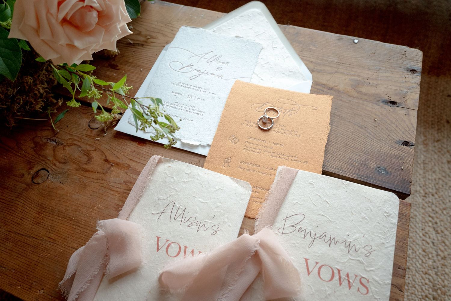 Wedding vow books with pink ribbons and ring on wooden table.