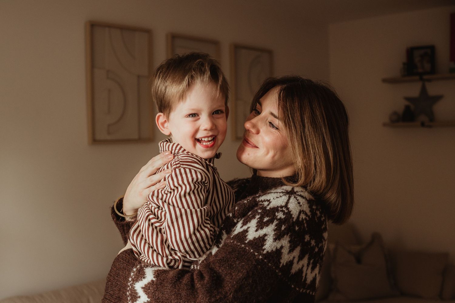 Tender moment between dad in red sweater and toddler wearing brown overalls.