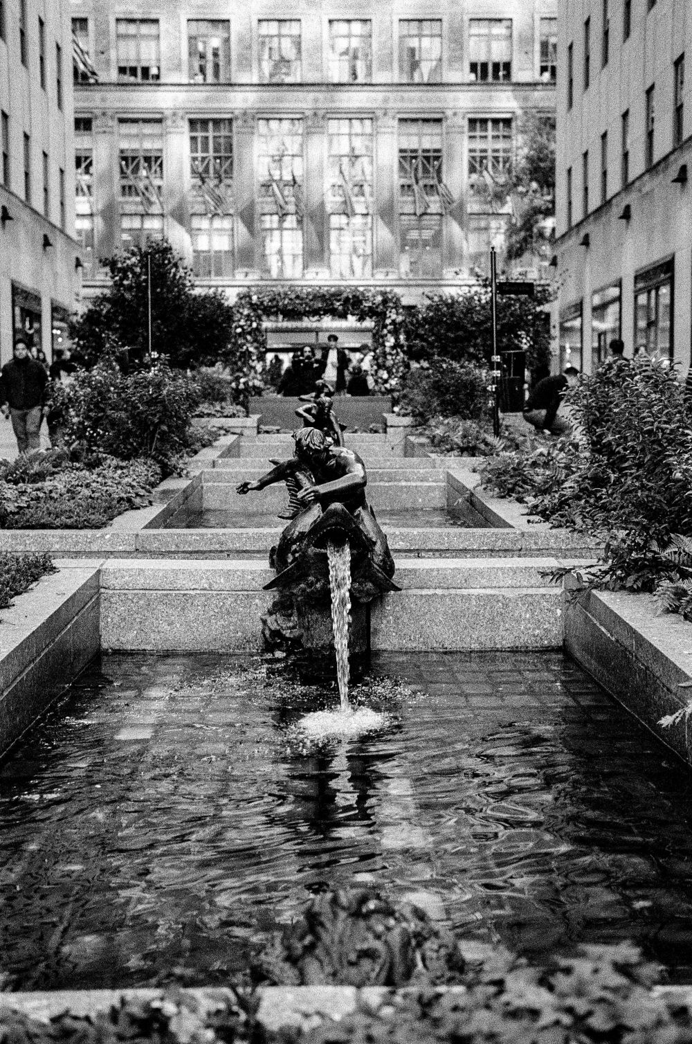 Courtyard fountain with bronze sculpture and reflective pool surrounded by urban architecture.