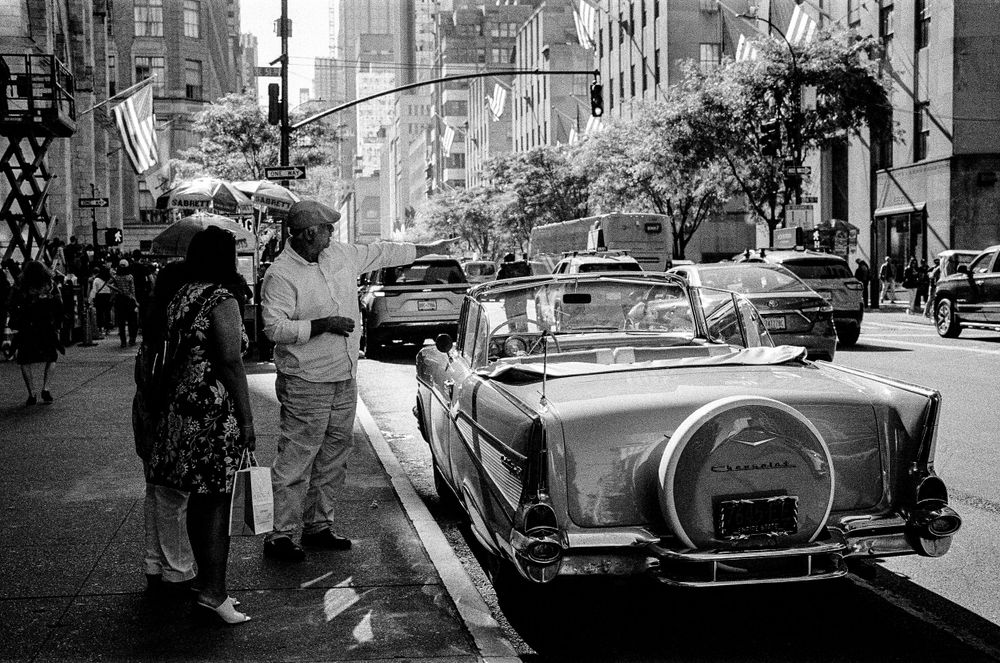 Vintage car parked on a rainy New York City street.
