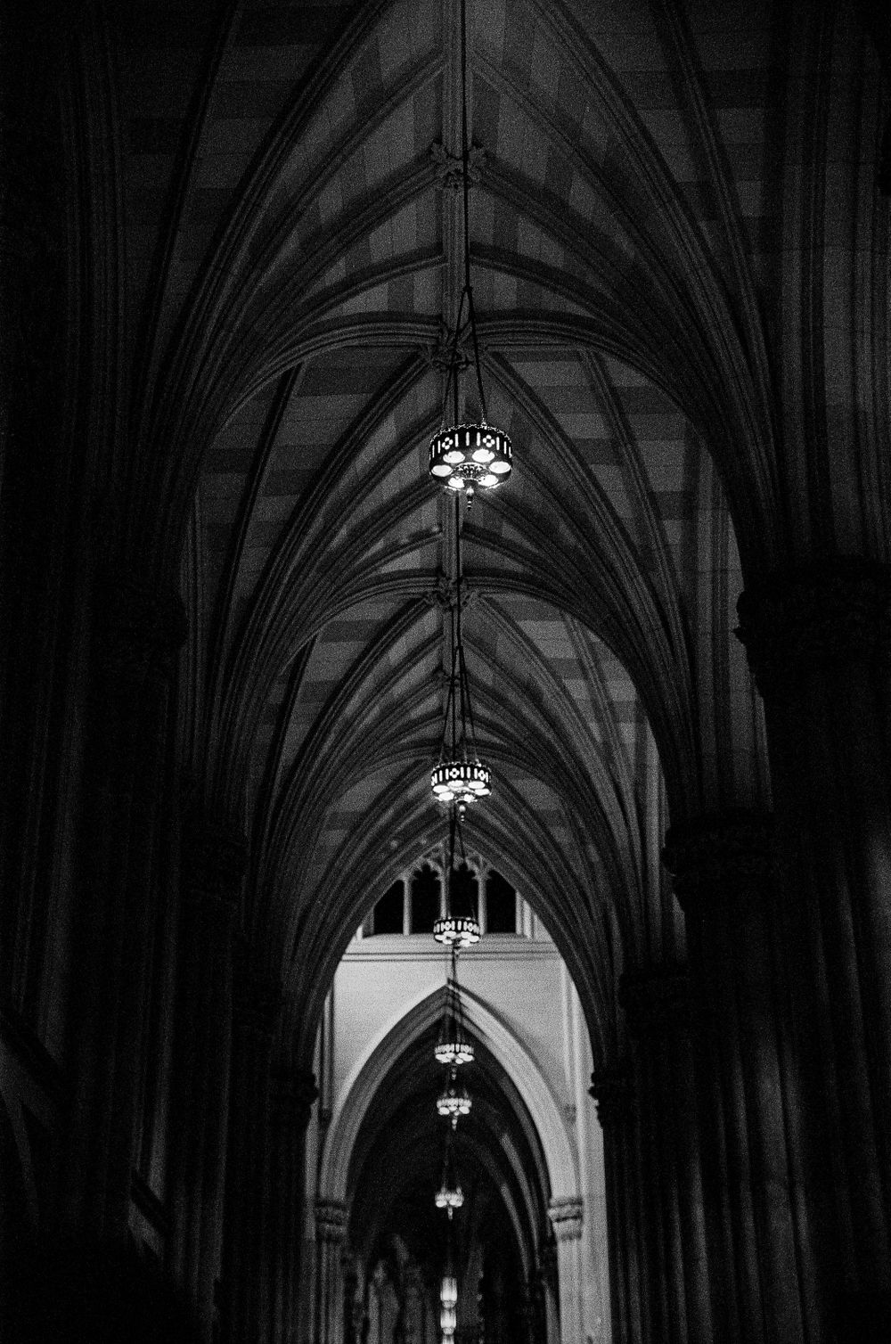 Gothic cathedral interior with vaulted ceilings and hanging chandeliers.