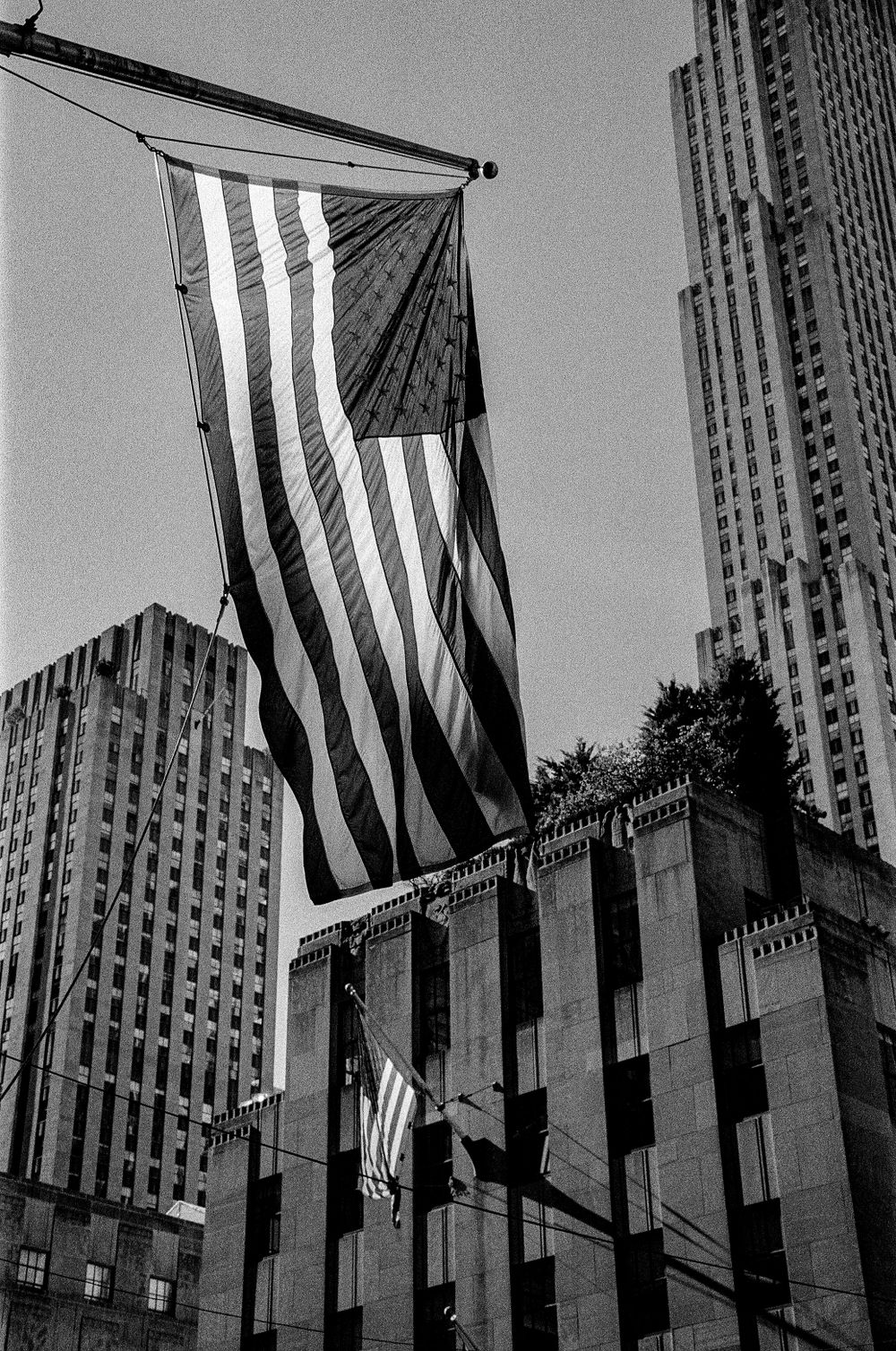 American flag waves in front of Rockefeller Center architecture.