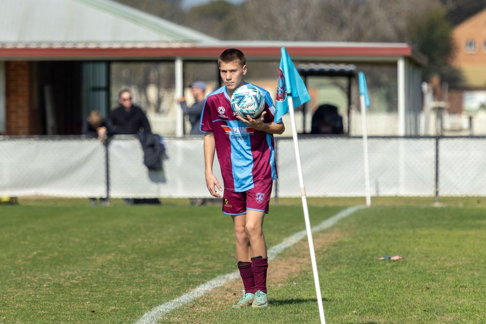 Soccer player in maroon and blue uniform prepares to throw in the ball from sideline.