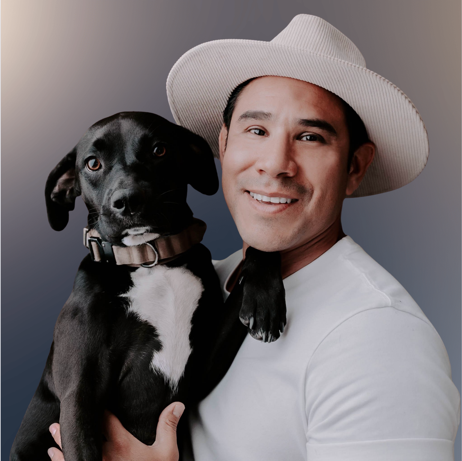 Professional headshot of person in white cowboy hat holding a black and white dog against neutral background.