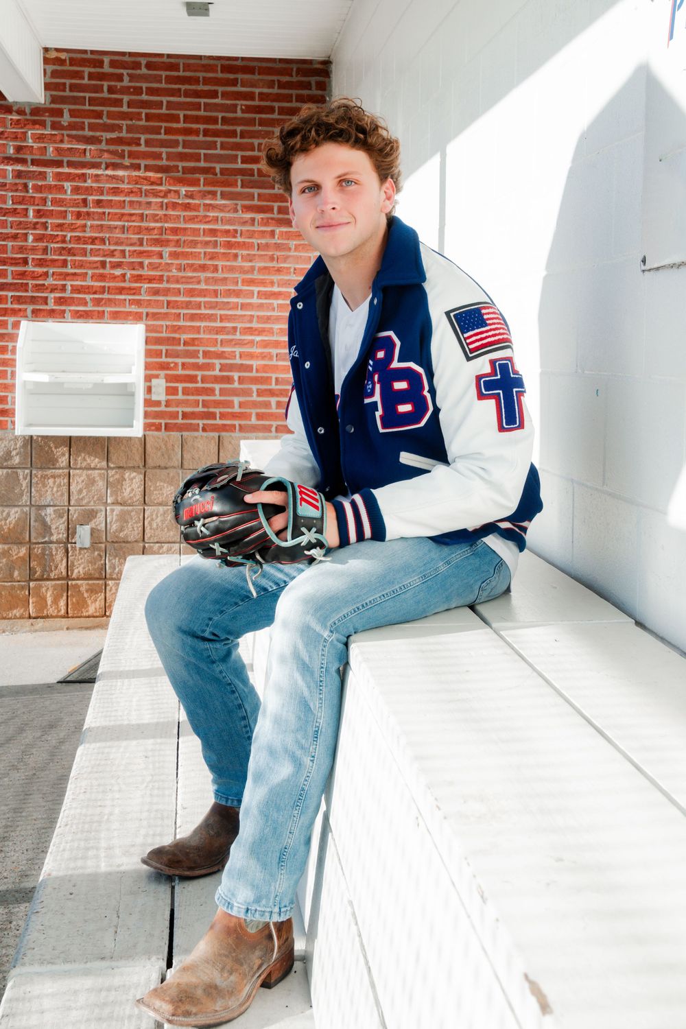 Varsity letterman jacket with BT patch and American flag displayed on brick wall background.