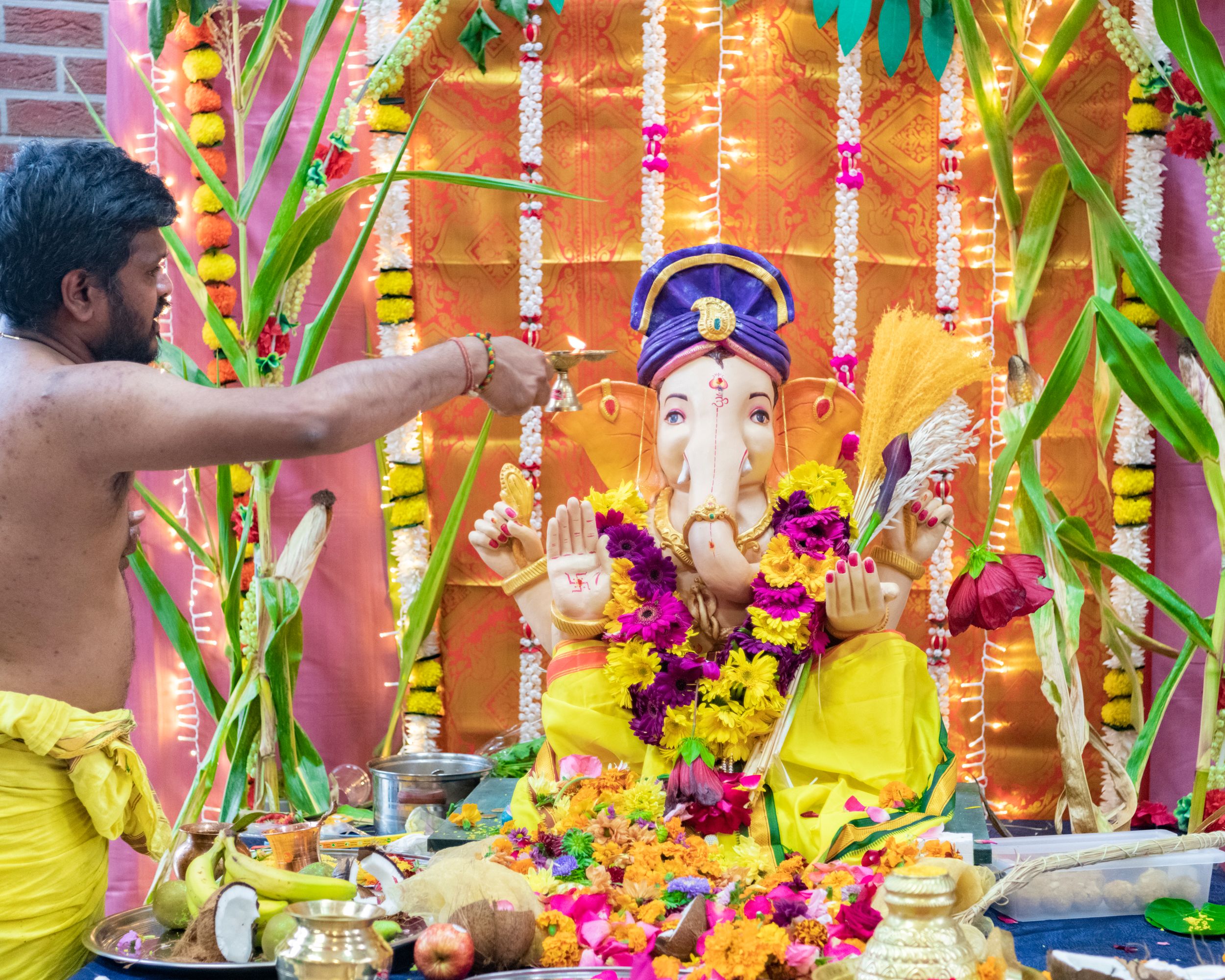 A colorful Ganesh Chaturthi celebration with bamboo decorations, flowers and religious offerings during a traditional ceremony.