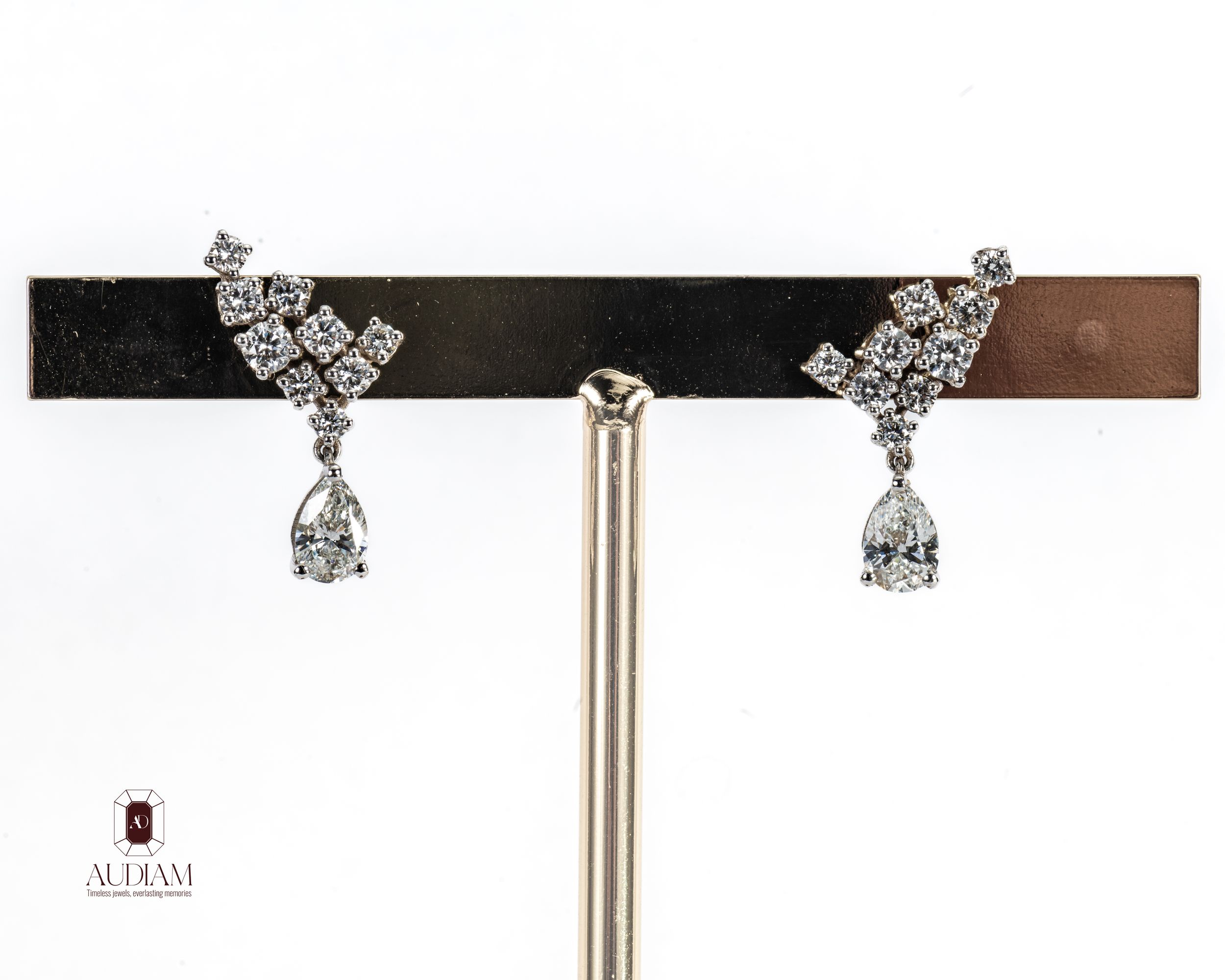 Elegant diamond drop earrings featuring pear-shaped crystals and cluster tops in silver-tone setting on display stand.