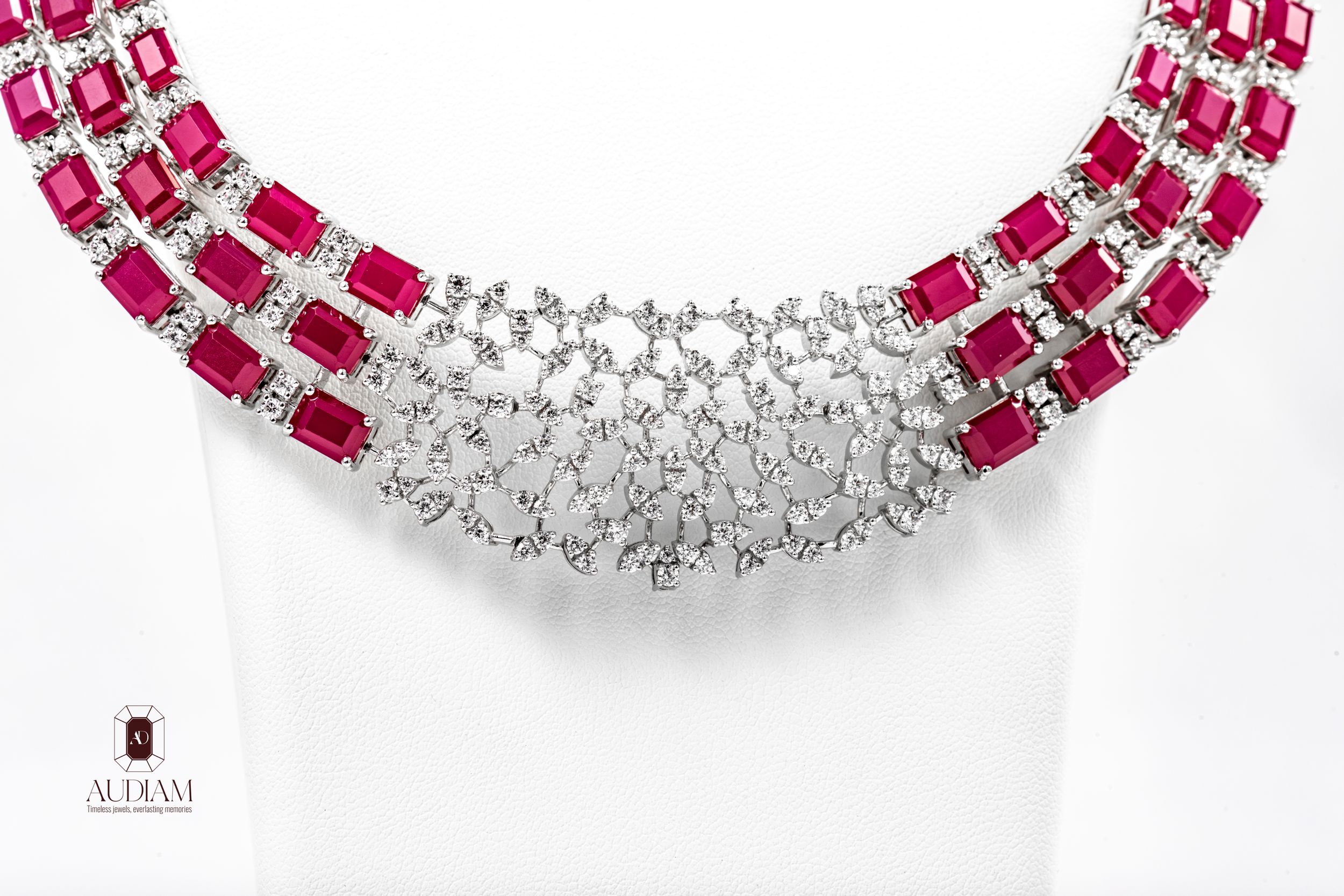 Elegant ruby and diamond necklace by Aldham, featuring emerald-cut rubies with intricate white gold settings.