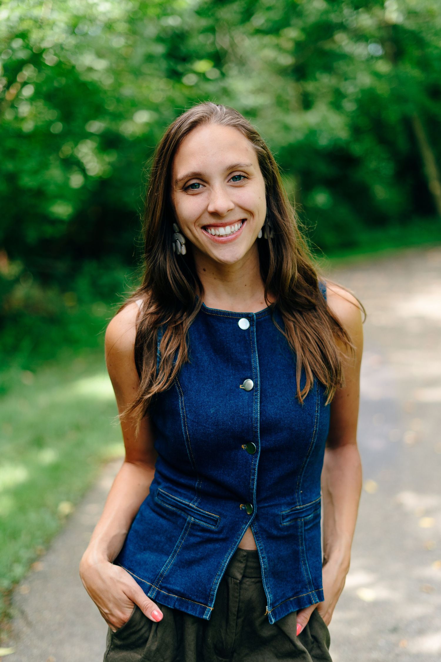 Woman in striped shirt poses against brick wall in urban setting.