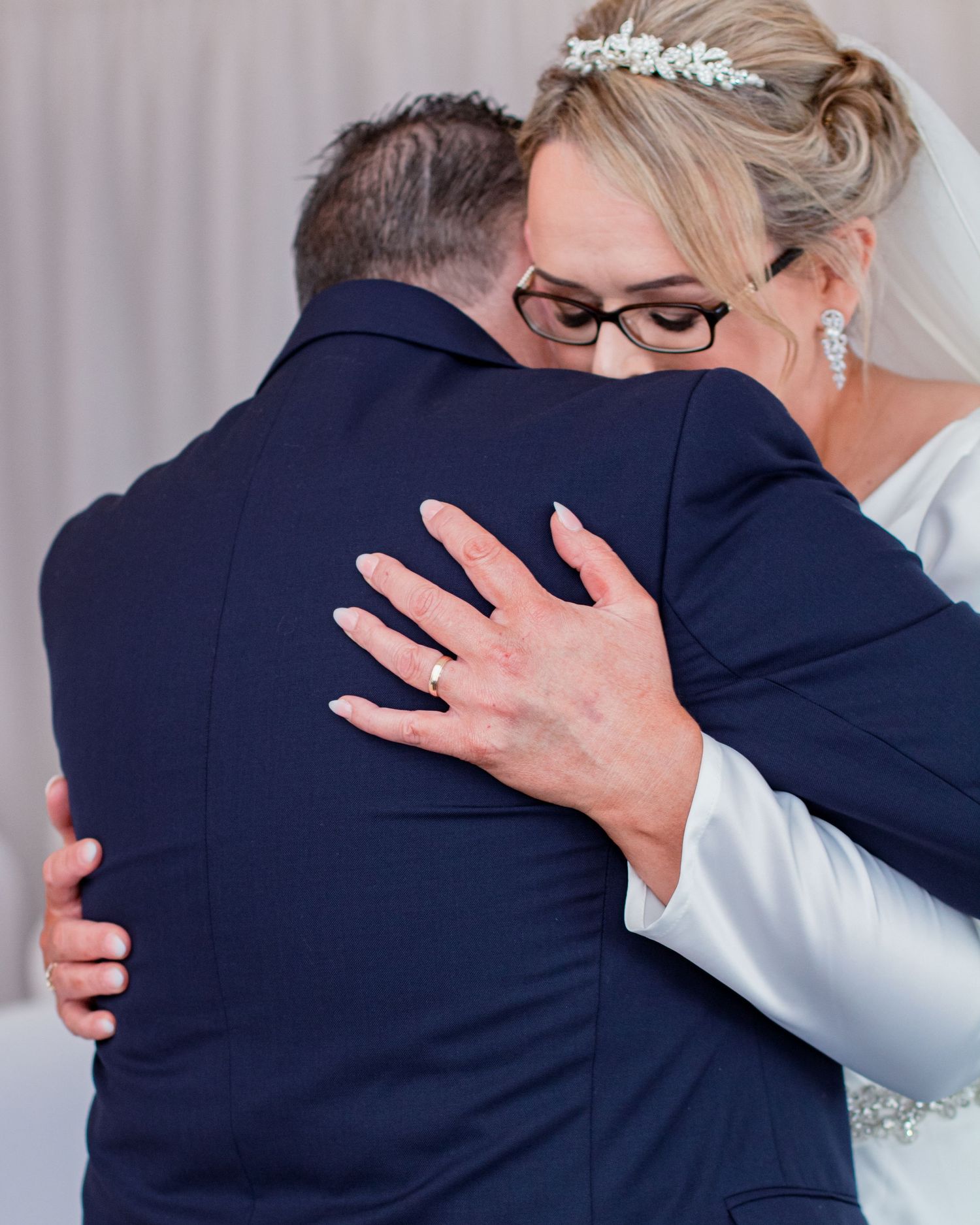 Two people embracing in formal attire during what appears to be a wedding celebration.