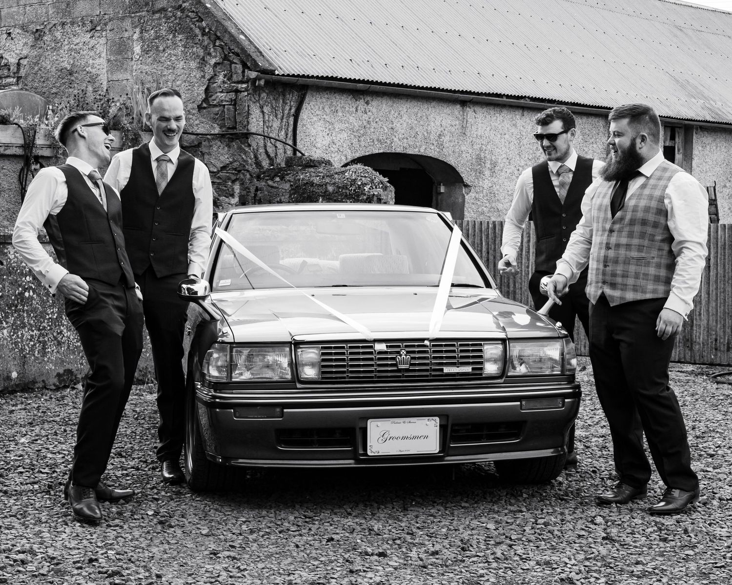 Vintage cars lined up at a wedding venue with guests gathered around.
